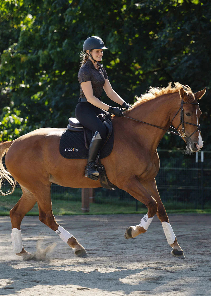 Rider wearing a brown riding shirt riding a horse