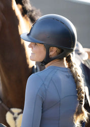 Side view of rider wearing a blue long sleeve riding top and helmet