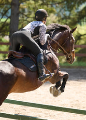 Rider wearing a patterned riding shirt jumping a horse