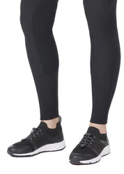 Close up view of a model wearing the Kerrits Microcord Knee Patch Pocket Tight in black with tennis shoes on a white background