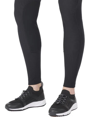 Close up view of a model wearing the Kerrits Microcord Knee Patch Pocket Tight in black with tennis shoes on a white background
