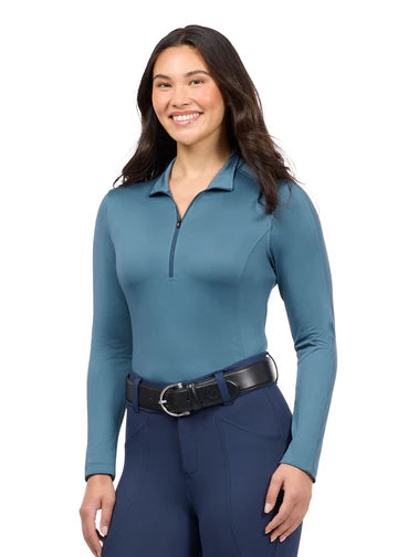 Woman wearing teal long sleeve riding shirt with riding tights, front view