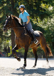 Rider wearing a bright blue polo shirt riding a horse in an arena