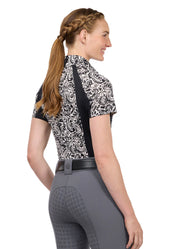 Woman wearing a black and white patterned short sleeve riding shirt, rear view
