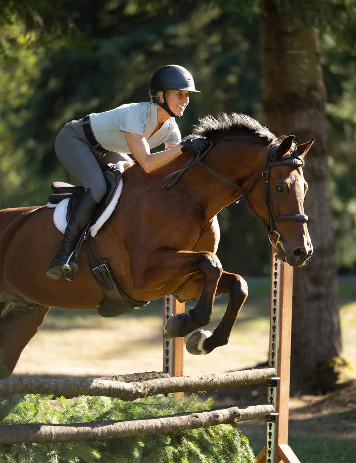 Rider jumping a horse while wearing gray knee patch breeches