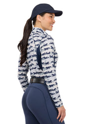 Woman wearing a horse print long sleeve riding shirt, rear view