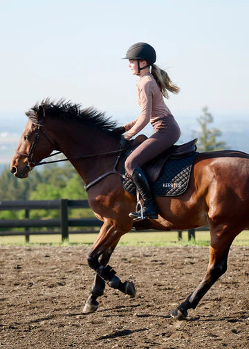 Rider cantering a horse while wearing brown riding tights
