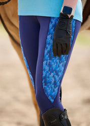 Close-up of rider’s leg wearing navy tights with blue patterned panel and tall boot
