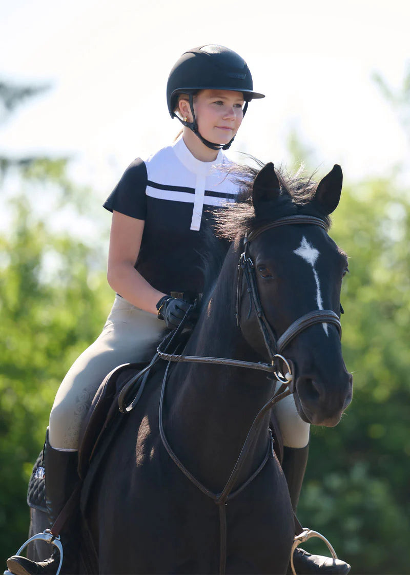 Rider wearing black short sleeve riding shirt with white stripe detail riding outdoors