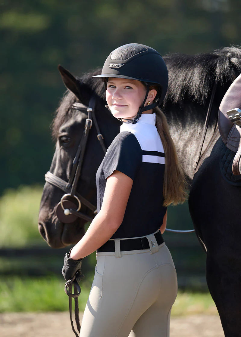 Rider wearing black short sleeve riding shirt with white stripe detail standing next to a horse