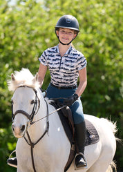 Girl wearing the Kids EquiBreeze Ice Fil Short Sleeve Shirt in the color Mist Brushstrokes while riding a white horse