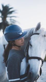 Angled front view of a female model wearing the atlantic KASK Star Lady Pure Shine Helmet while standing next to a gray horse