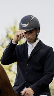 Angled front view of a male rider wearing the anthracite Kask Dogma Chrome Helmet while riding a horse