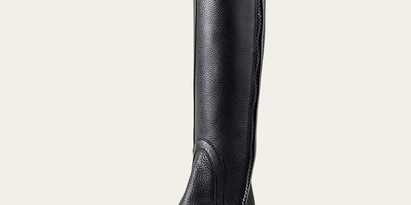 Angled side view of the black Ariat Breeze Half Chap on a plain background
