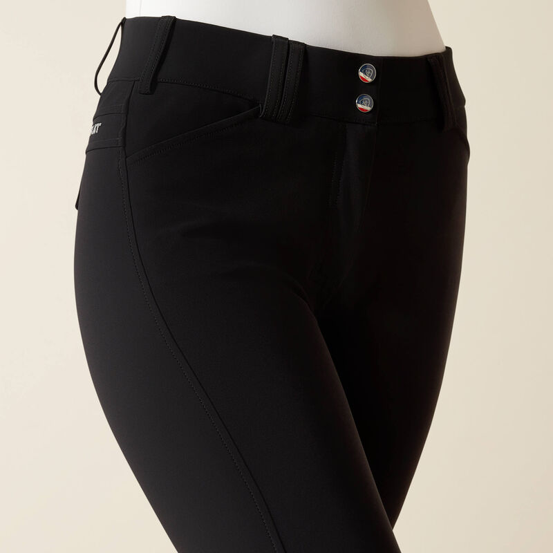Close-up angled front view of a model wearing the black Ariat Tri Factor Grip Knee Patch Breech on a plain background