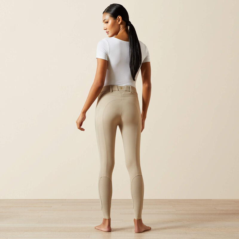 Full body back view of a female model wearing the tan Ariat Tri Factor NT Knee Patch Breech and white shirt in a studio setting