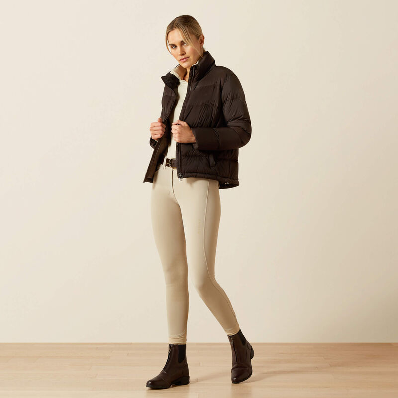 Full body front view of model wearing the Ariat Ultrapuff Down Jacket in brown and tan breeches in a studio setting