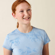 Close up front view of young girl wearing the Ariat Youth Mirage T-Shirt in blue in a studio setting