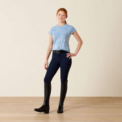 Full body front view of young girl wearing the Ariat Youth Mirage T-Shirt in blue and blue breeches in a studio setting