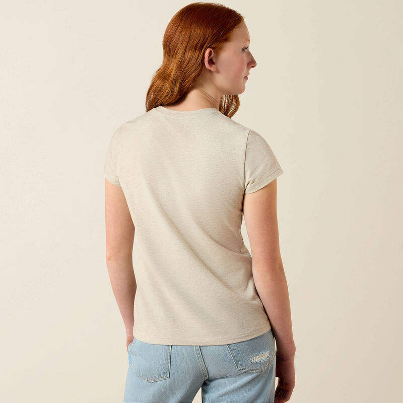 Back view of a young girl wearing the Ariat Youth Floral Leap T-Shirt in tan in a studio setting