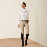 Full body front view of model wearing the Ariat Breathe Long Sleeve Showshirt in white, tan breeches, and black tall boots in a studio setting