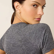 Close up back view of a model looking over her shoulder wearing the Ariat Sustain Short Sleeve Baselayer in gray
