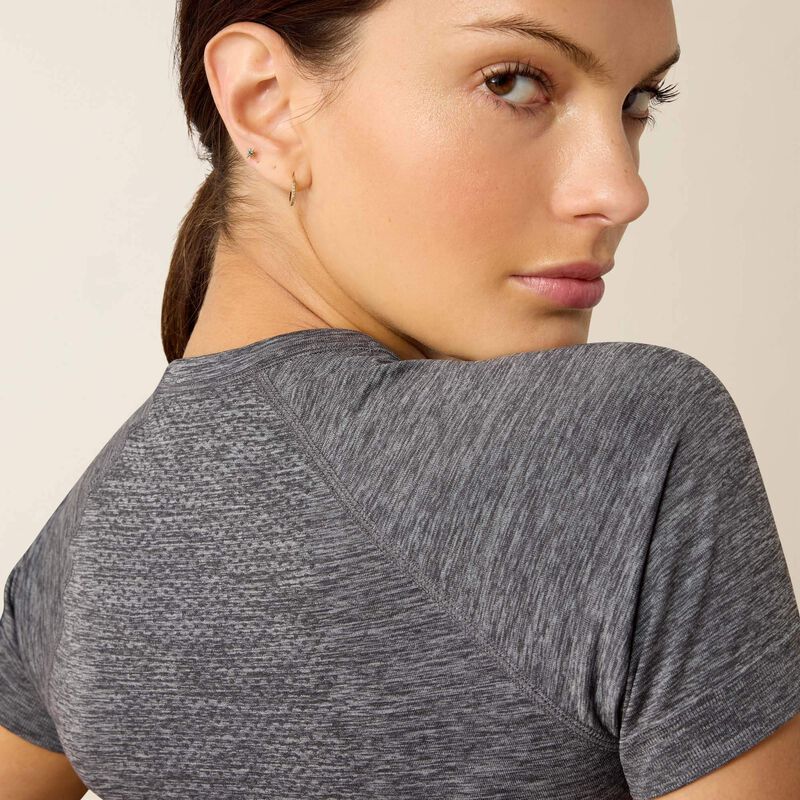 Close up back view of a model looking over her shoulder wearing the Ariat Sustain Short Sleeve Baselayer in gray