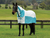Angled front view of a dark colored horse wearing the white/mint Weatherbeeta Kool Coat Cotton Airstream II Detach-A-Neck while standing in a green pasture