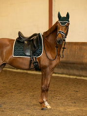 Side view of a chestnut horse wearing the green PS of Sweden Heart Dressage Saddle Pad under a black saddle
