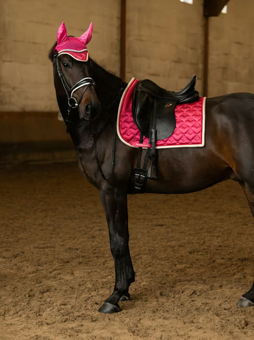 Side view of a black horse wearing the pink PS of Sweden Heart Dressage Saddle Pad under a black saddle