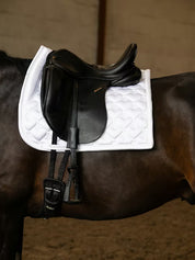 Side view of a black horse wearing the white PS of Sweden Heart Dressage Saddle Pad under a black saddle