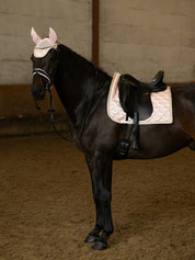 Side view of a black horse wearing the white PS of Sweden Heart Dressage Saddle Pad under a black saddle