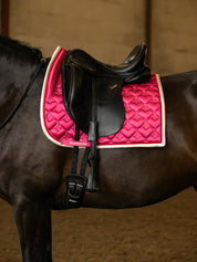 Side view of a black horse wearing the pink PS of Sweden Heart Dressage Saddle Pad under a black saddle