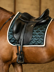 Side view of a chestnut horse wearing the green PS of Sweden Heart Dressage Saddle Pad under a black saddle