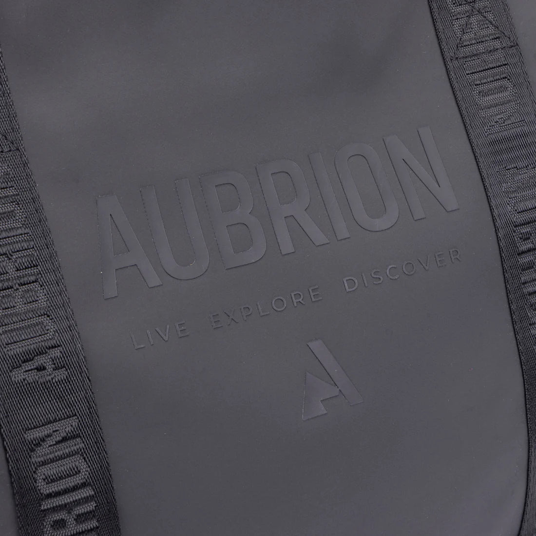 Close-up view of the tone-on-tone name Aubrion and "Live Explire Discover" on the front of the Aubrion React Tote Bag