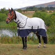 Side view of bay horse standing outside wearing the Shires Tempest Original Summer Shield Set in white and navy