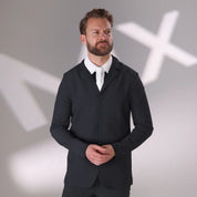 Front view of a male model wearing the black Aubrion Men's Optima MX Show Coat with the background being a blurry white MX on a gray