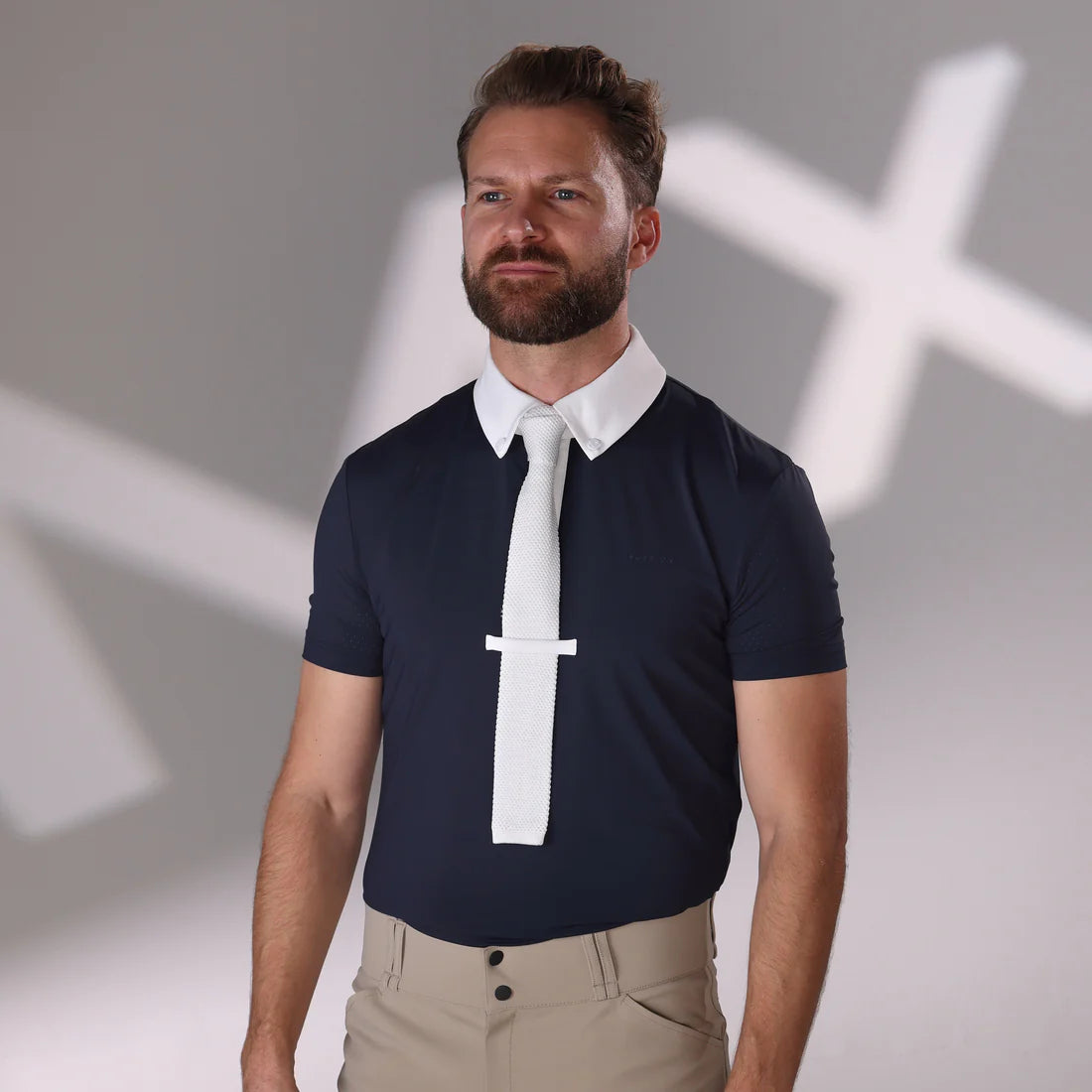 Front view of a male model wearing the navy Aubrion Men's Optima MX Button Show Shirt with a blurry MX in white on the gray backgorund