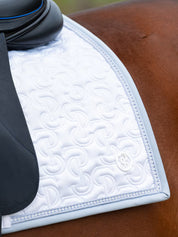 Close-up view of the back corner of the white PS of Sweden Crystal Satin Dressage Saddle Pad on a white background