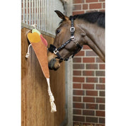 Side view of a horse smelling the HKM Ice Cream Horse Toy that is hanging in a stall