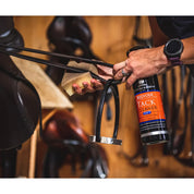 Close-up view of someone clearning a stirrup leather using a spong and the Carr & Day & Martin Belvoir Tack Cleaner in a tack room