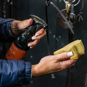 Close-up view of a female model spraying Carr & Day & Martin Belvoir Tack Cleaner onto a tack sponge