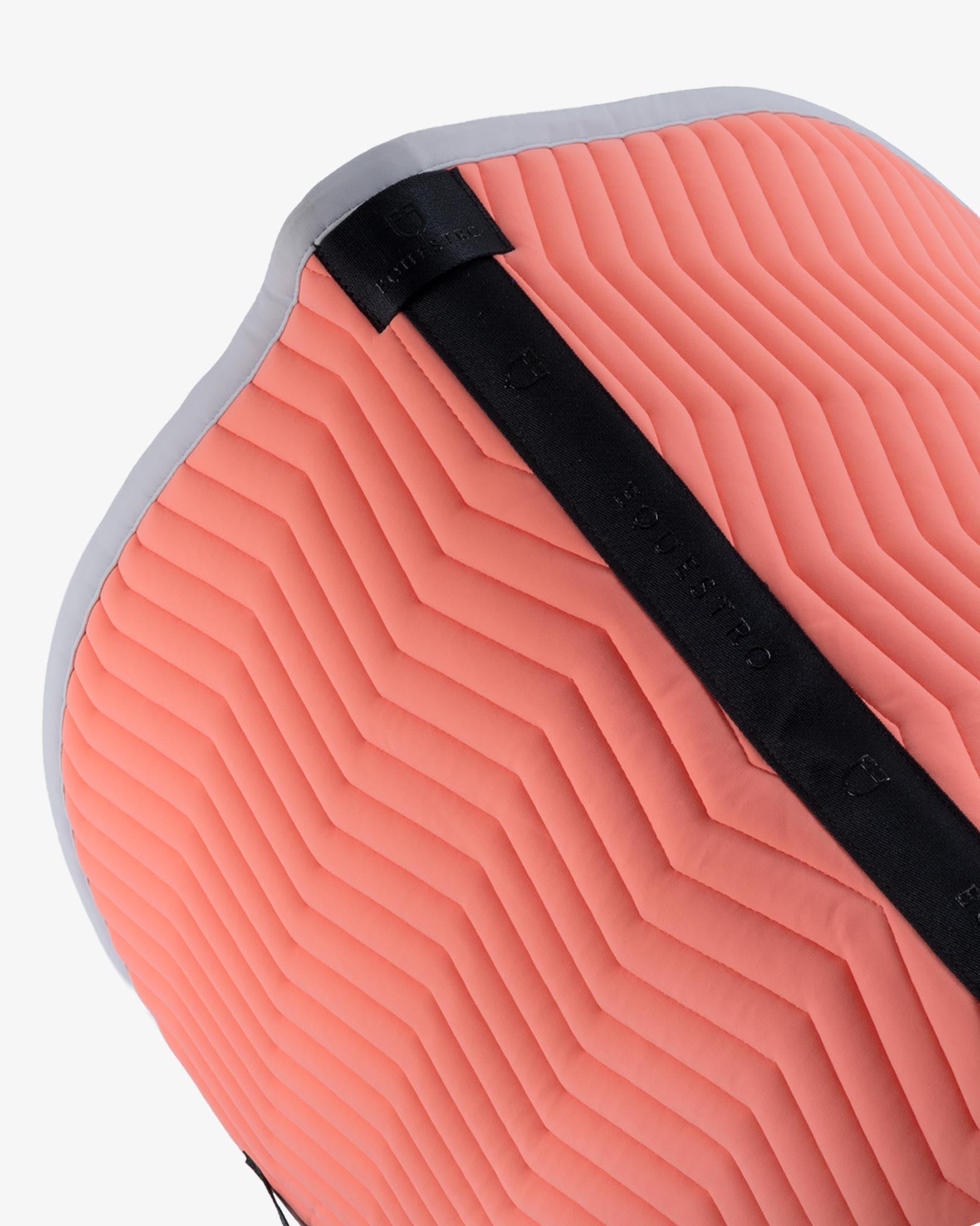 Close up top view of the spine of the Equestro Wave Quilting Jumping Saddle Pad In Technical Fabric in a coral color on a white background