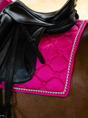 Side view of a horse wearing the hot hibiscus PS of Sweden The Original Monogram Dressage Saddle Pad under a black dressage saddle