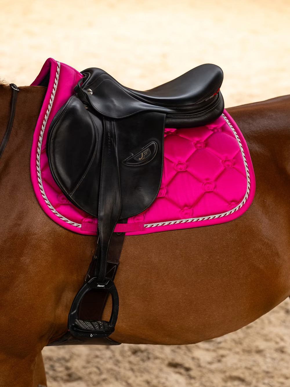 Side view of a horse wearing the hot hibiscus PS of Sweden The Original Monogram Jump Saddle Pad under a brown saddle