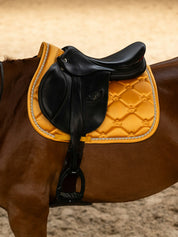 Side view of a horse wearing the Sunburst Sorbet PS of Sweden The Original Monogram Jump Saddle Pad under a brown saddle