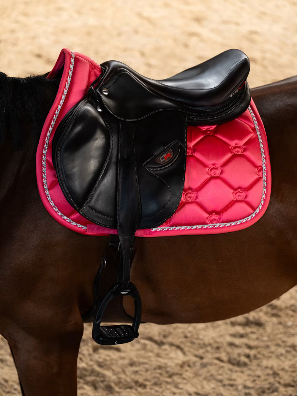 Side view of a horse wearing the Pink Guava PS of Sweden The Original Monogram Jump Saddle Pad under a brown saddle