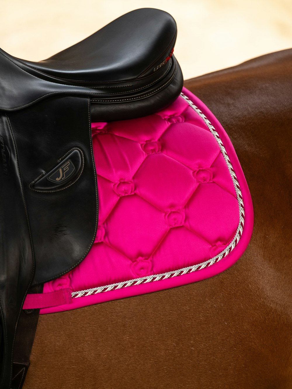 Close-up view of the back of the Hot Hibiscus PS of Sweden The Original Monogram Jump Saddle Pad under a brown saddle