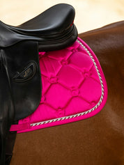 Close-up view of the back of the Hot Hibiscus PS of Sweden The Original Monogram Jump Saddle Pad under a brown saddle