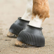 Close-up side view of a horse wearing the black KL Select Italian Pull On Bell Boots while standing on sand